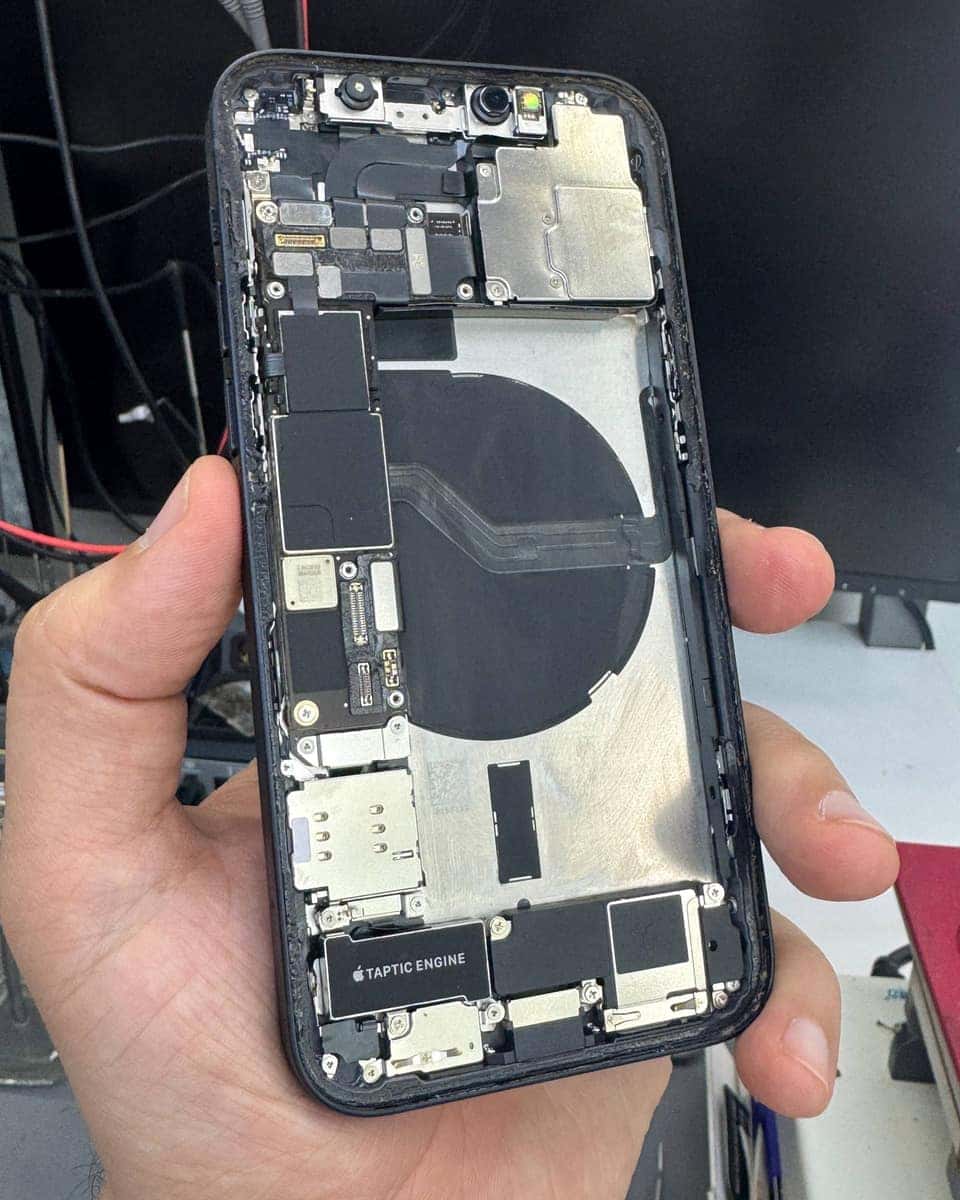Разобранный iPhone в руке мастера перед сборкой